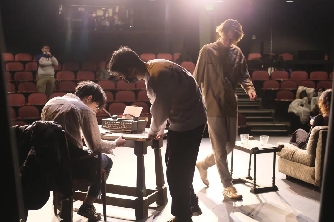 《漫长的告别》排练现场，成员围在舞台道具旁讨论 / May Drama members working together around a stage prop during rehearsal